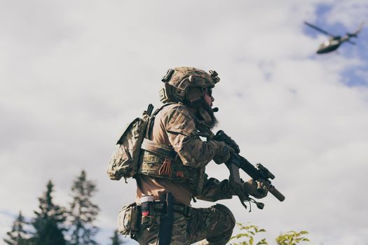 War concept. A bearded soldier in a special forces uniform fighting an enemy in a forest area. Selective focus. High-quality photo