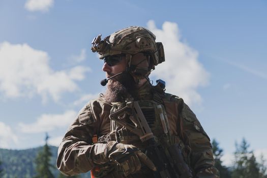 War concept. A bearded soldier in a special forces uniform fighting an enemy in a forest area. Selective focus. High-quality photo