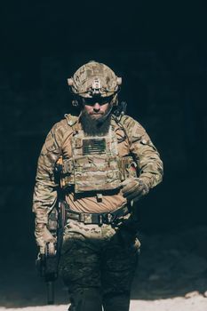 A bearded soldier in a special forces uniform walks through an abandoned building after a successful mission. Selection focus. High-quality photo