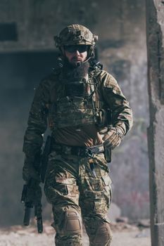 A bearded soldier in a special forces uniform walks through an abandoned building after a successful mission. Selection focus. High-quality photo