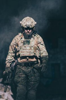 A bearded soldier in a special forces uniform walks through an abandoned building after a successful mission. Selection focus. High-quality photo