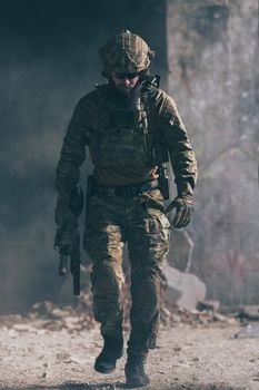 A bearded soldier in a special forces uniform walks through an abandoned building after a successful mission. Selection focus. High-quality photo