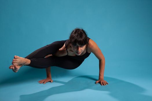 Portrait of fit person standing in hand training arm balance working at body endurance stretching muscles. Active woman in sportwear practicing yoga position during sport workout. Pilates concept