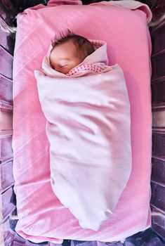 High angle shot of a newly born baby girl wrapped in a blanket in the hospital.