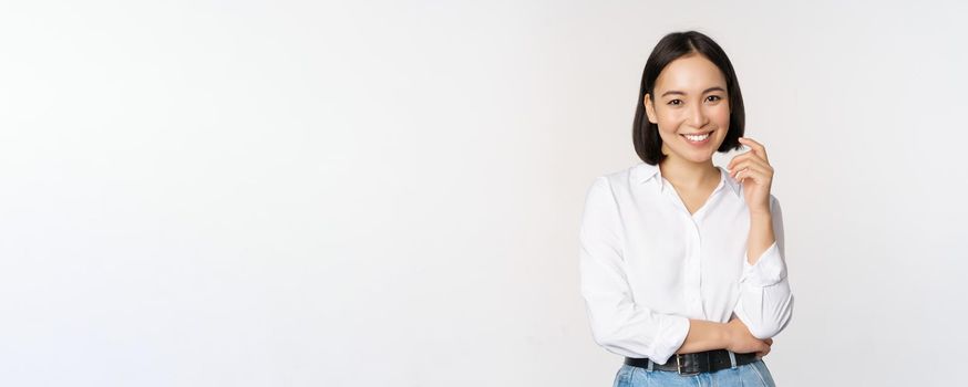 Young asian woman, professional entrepreneur standing in office clothing, smiling and looking confident, white background.