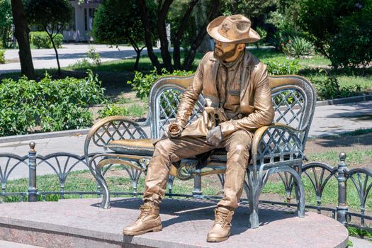 a man-statue is sitting on a bench. High quality photo