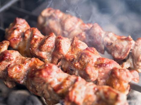 Grilled skewers of meat on the coals, with smoke. The street food.