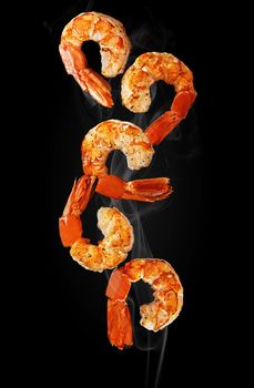 Closeup of hot grilled shrimp tails hovering in white haze on black background. Vertical image