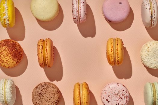 Top view of macarons symmetrically arranged with one missing in center on pink background pattern