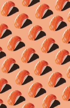 Colorful food pattern of nigirizushi with smoked salmon isolated on pinkish orange background. Concept of traditional Japanese cuisine
