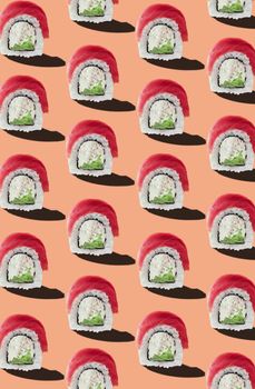 Philadelphia rolls with raw tuna slice and traditional filling of cream cheese and cucumber on pinkish orange background. Colorful seamless food pattern