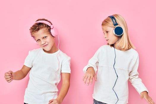 Funny children stand next to in headphones pink color background. High quality photo