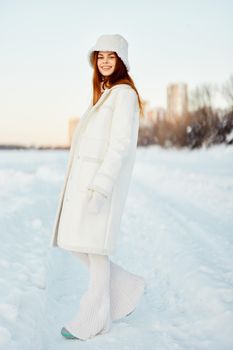 young woman in a white coat in a hat winter landscape walk Fresh air. High quality photo