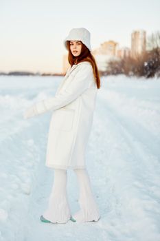 young woman in a white coat in a hat winter landscape walk Fresh air. High quality photo