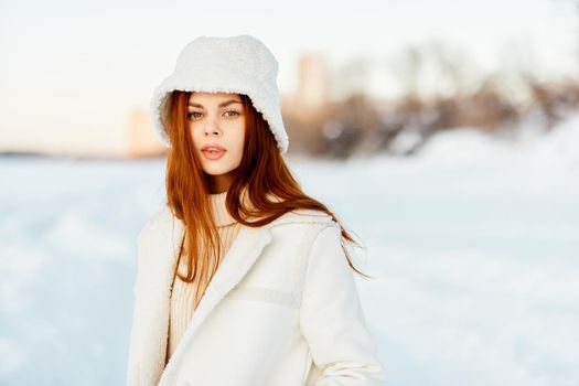 pretty woman in a white coat in a hat winter landscape walk nature. High quality photo