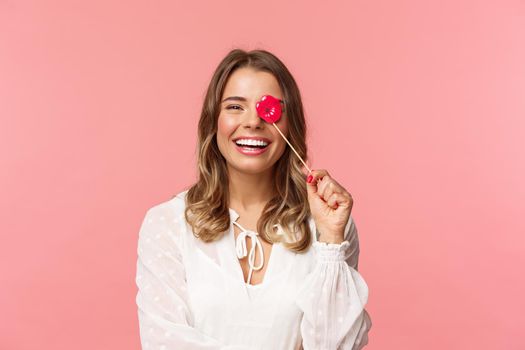 Spring, happiness and celebration concept. Close-up portrait of funny and carefree young beautiful blond girl having fun at party with girlfriends, holding lips stick and laughing, pink background.