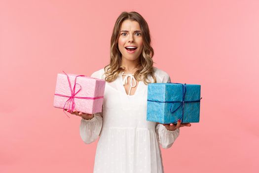 Holidays, celebration and women concept. Portrait of surprised and impressed blond girl didnt expect receive so many presents, holding two wrapped gifts and smiling camera astonished.