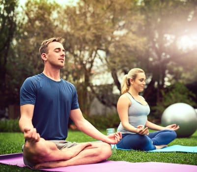 Shot of a young couple practising yoga together outdoors.