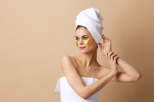 portrait woman with a towel on his head gesturing with his hands skin care beige background. High quality photo