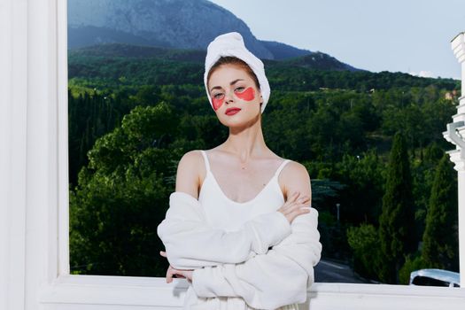 Woman in a bathrobe stands in a robe against the backdrop of mountains with patches on his face close-up. High quality photo