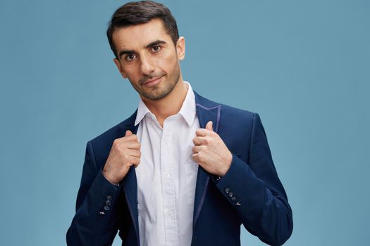 successful man in a stylish business blue suit holding on to the collar confident look of a professional blue background copy space. High quality photo