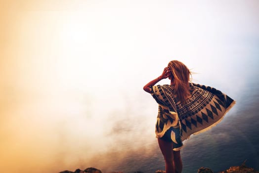 Rearview shot of an unidentifiable young woman admiring a foggy view from the top of a mountain.