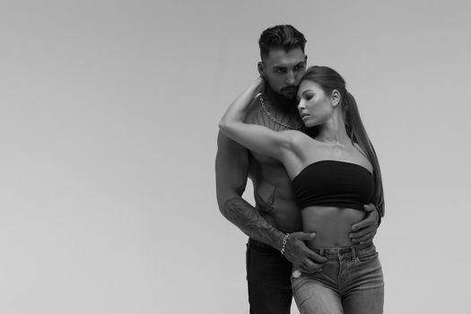 Black and white tattooed shirtless man and seductive topless woman looking away