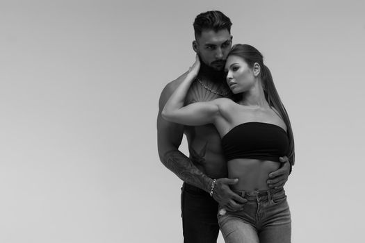 Black and white tattooed shirtless man and seductive topless woman looking away