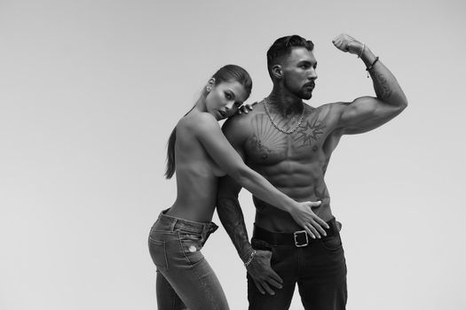 Black and white tattooed shirtless man and seductive topless woman looking away