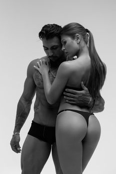 Black and white tattooed shirtless man and seductive topless woman looking away