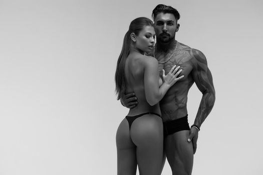 Black and white tattooed shirtless man and seductive topless woman looking away