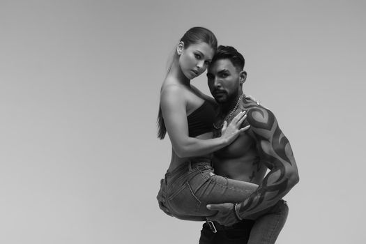 Black and white tattooed shirtless man and seductive topless woman looking away