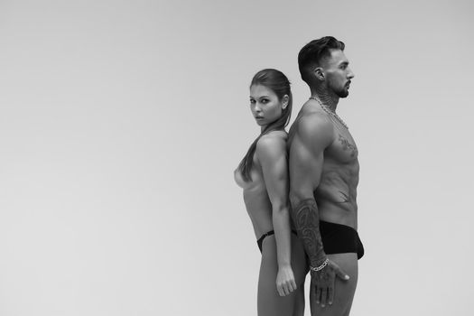 Black and white tattooed shirtless man and seductive topless woman looking away