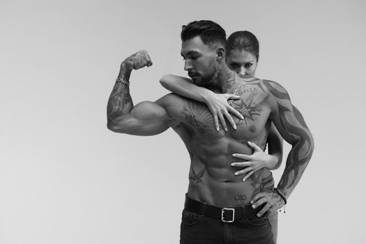 Black and white tattooed shirtless man and seductive topless woman looking away