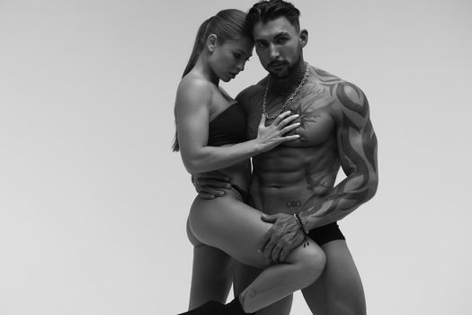 Black and white tattooed shirtless man and seductive topless woman looking away