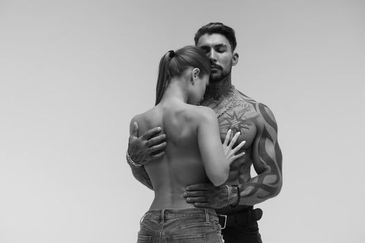 Black and white tattooed shirtless man and seductive topless woman looking away