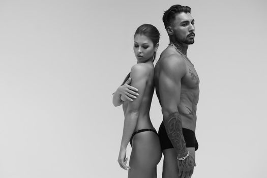 Black and white tattooed shirtless man and seductive topless woman looking away