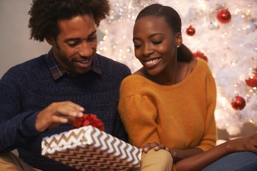 Shot of a loving young couple unwrapping gifts on Christmas.