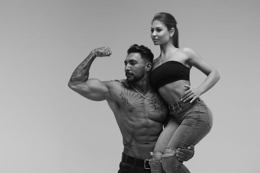 Black and white tattooed shirtless man and seductive topless woman looking away