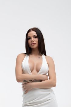 Young stylish seductive female in trendy white dress with low neckline looking erotically at camera