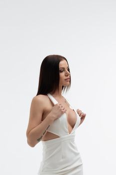 Young stylish seductive female in trendy white dress with low neckline looking erotically at camera