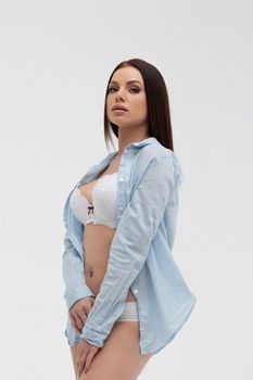 Young sensual woman with straight hair in white underwear and blue shirt looking at camera