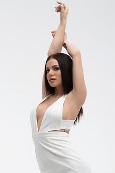 Young stylish seductive female in trendy white dress with low neckline looking erotically at camera