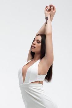 Young stylish seductive female in trendy white dress with low neckline looking erotically at camera