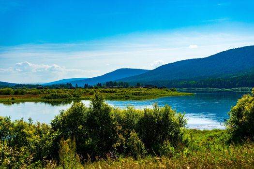 Landscape of the river bank in Siberia. bright juicy colors hilly riverbank and blue clouds.