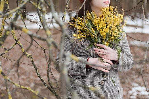 beautiful portrait of a young woman with mimosa flowers outdoors