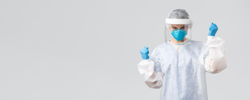 Covid-19, preventing virus, healthcare workers and quarantine concept. Confident doctor in personal protective equipment, face mask, cheering, invent coronavirus vaccine, determined cure patient.