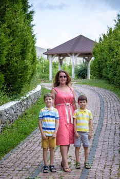 Young woman having fun playing in the park with their children. Boys of primary school age. The family is surrounded by picturesque plants. Games outdoor useful to all.