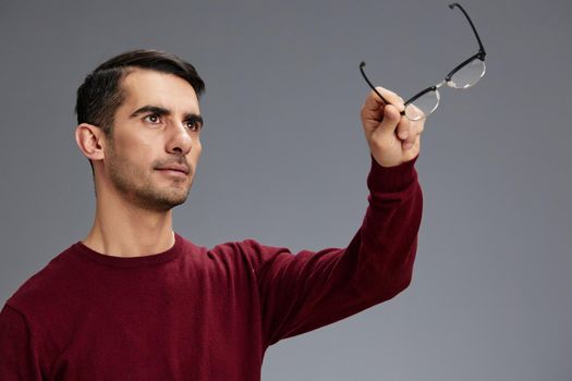 businessman holding glasses in front of him looking up in a sweater posing glasses emotions elegant style. High quality photo