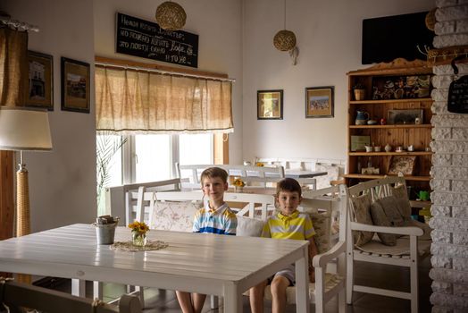 Modern cafe interior style, eco environmental with plant on wall, coffee shop. Two children sitting on bench near table waiting for tasty meal.